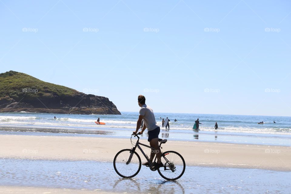 Young man riding a bike on the beach