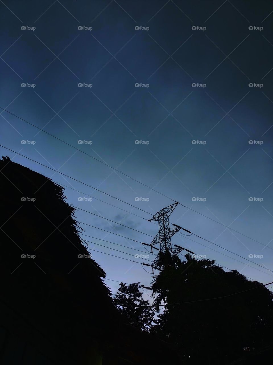 High voltage transmission towers with 
dark sky background at afternoon.