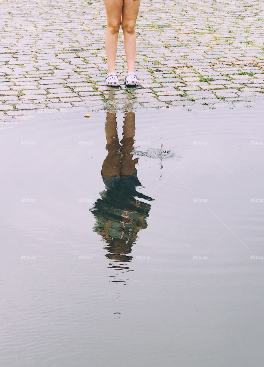 Reflection of a person throwing a stone in a water pond 