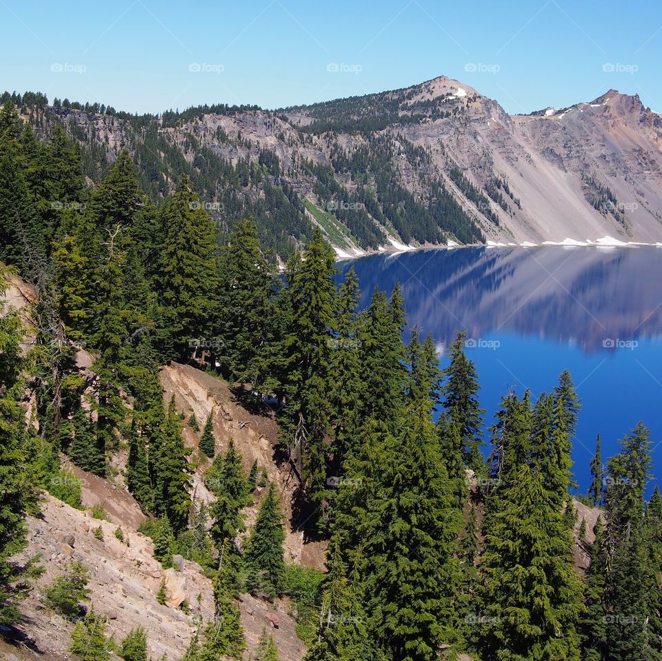 The rugged rim reflecting in the stunning Crater Lake on a beautiful summer morning in Southern Oregon. 