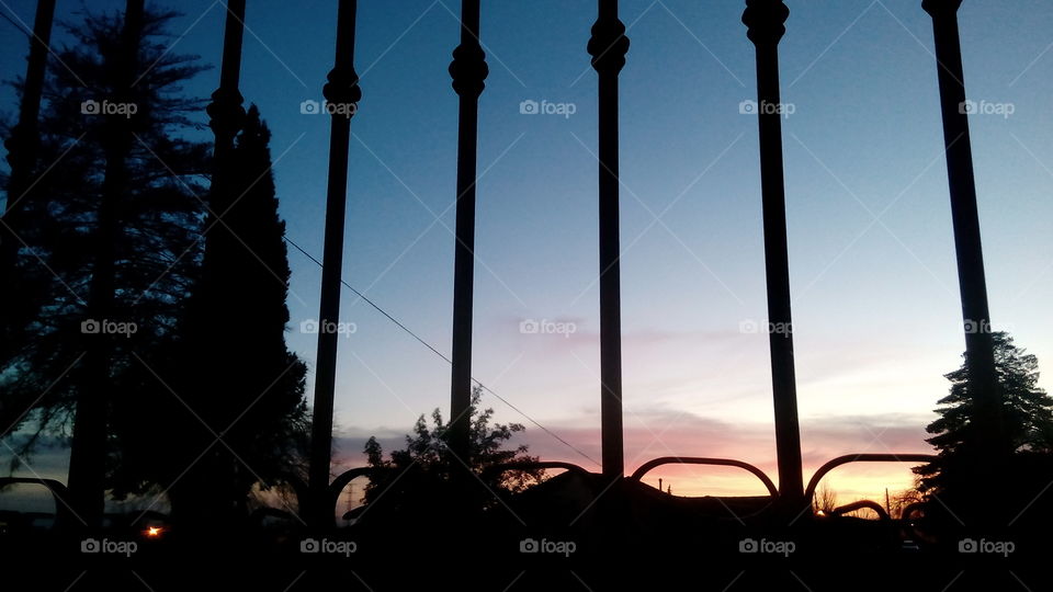 An image captured during the night between the columns of a fence. The sky has beautiful colors!