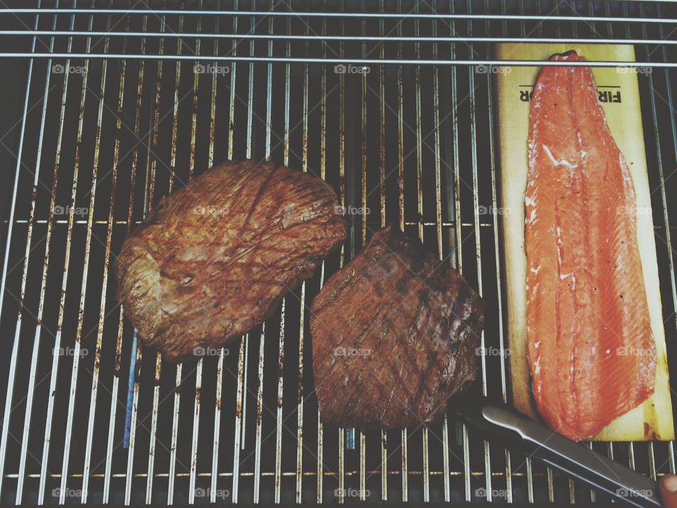 Red meat on the grill. Steaks and salmon cooking on the grill