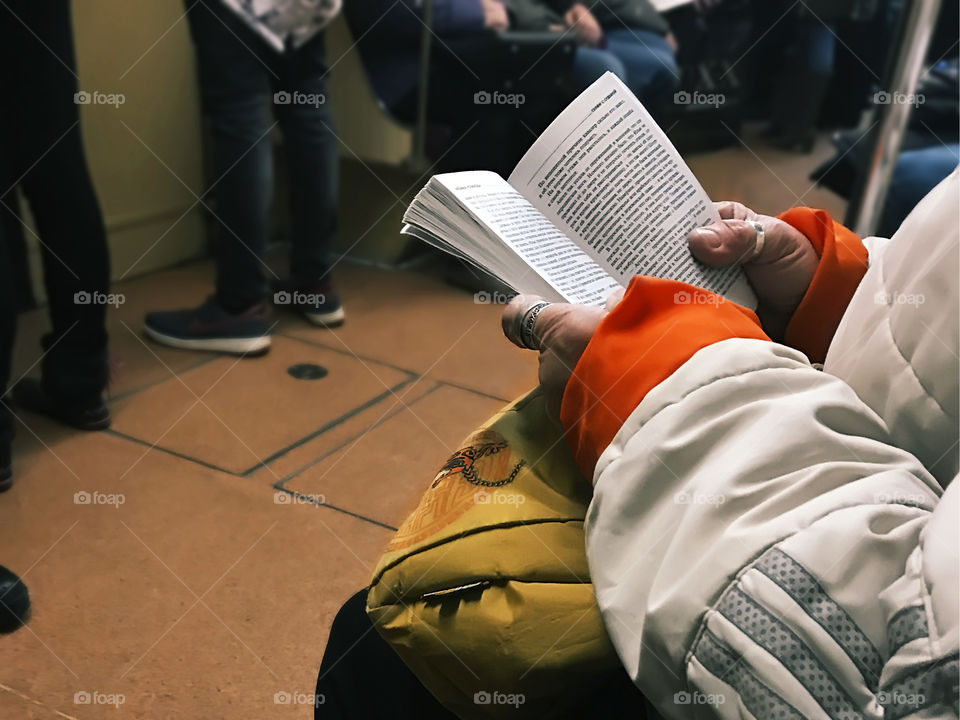 Senior woman reading a book while traveling by subway train 