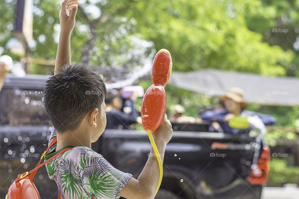 Asian boy holding a water gun play Songkran festival or Thai new year in Thailand.