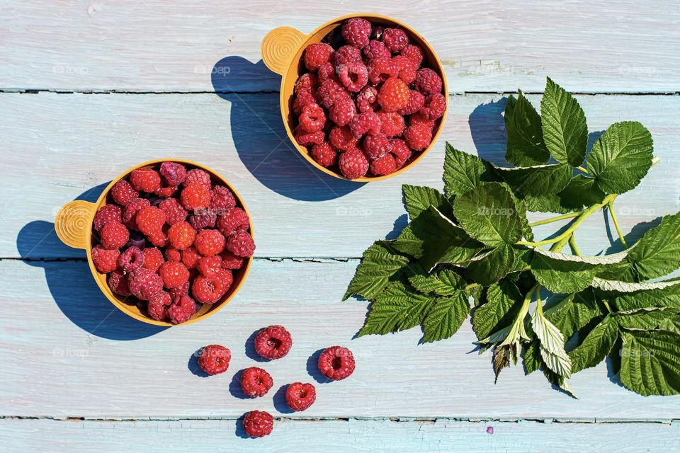 Food flat lay raspberries in a round bowl on wooden background 