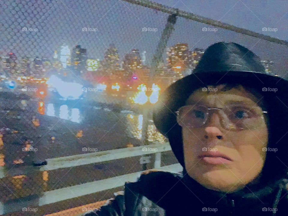 This is a self portrait photographed during the twilight hour in the pedestrian lane of the “Pulaski Bridge” at “Newtown Creek” in LIC, Queens seen from the “Greenpoint”, Bklyn side of the bridge. 2019. Hypnotic Productions