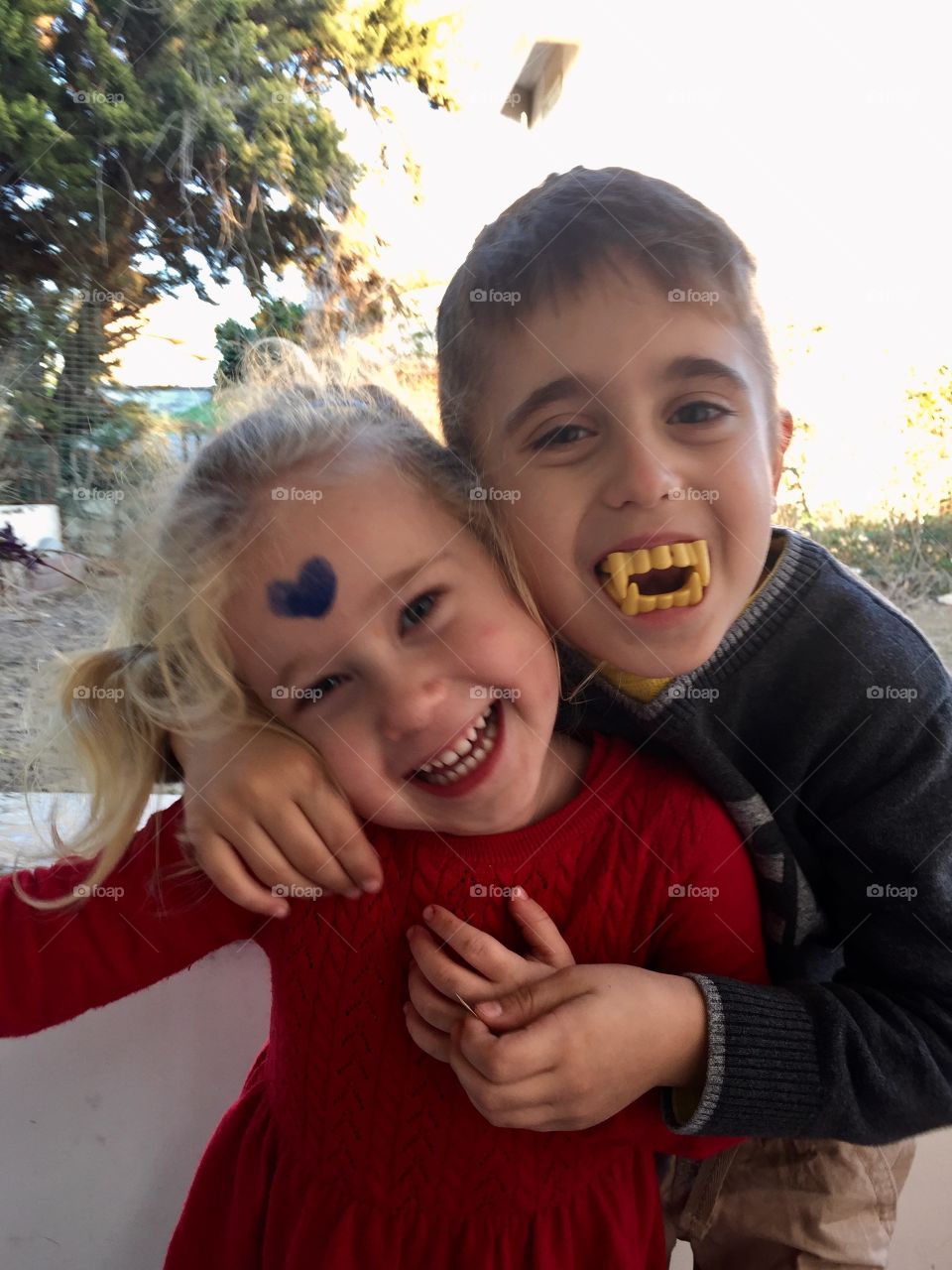 Boy wearing vampire teeth playing with sister