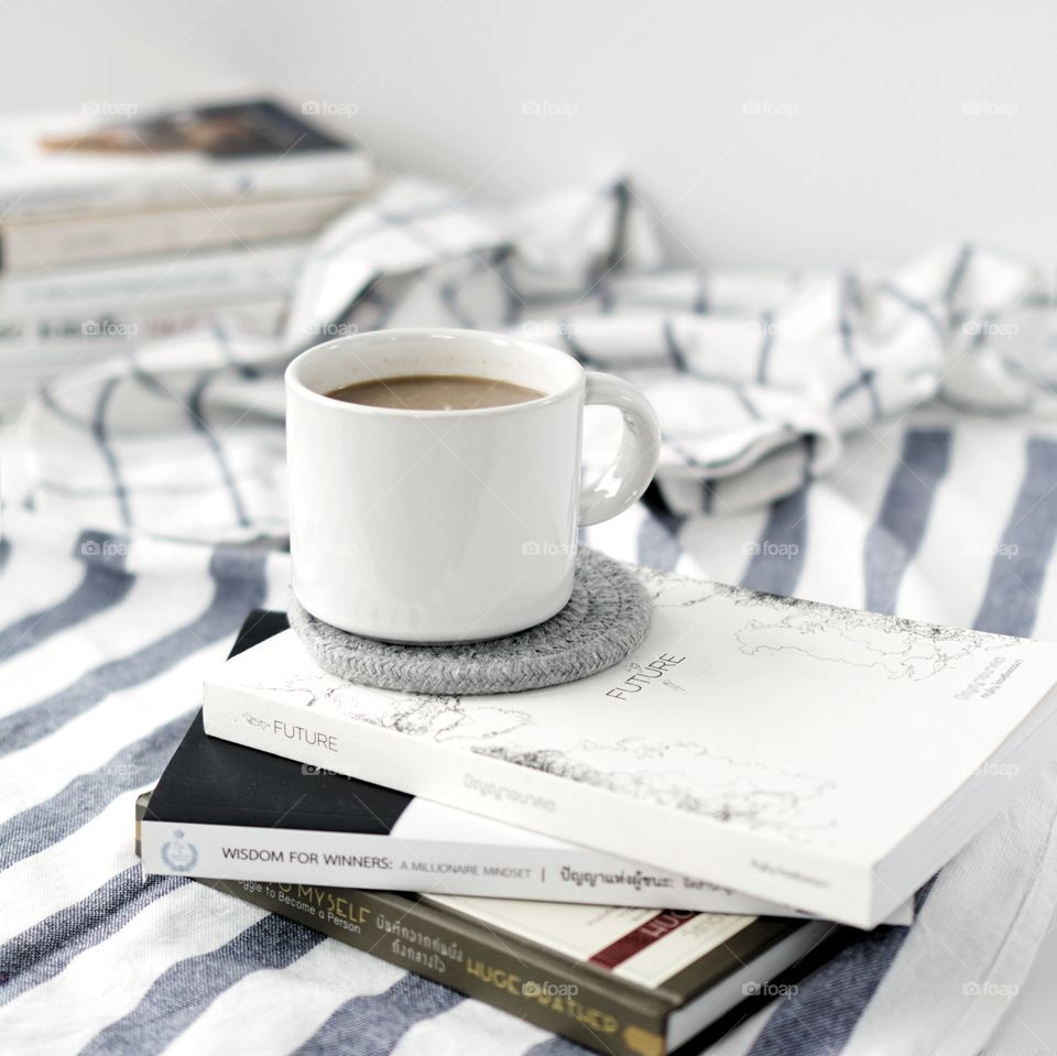 Hot coffee in a white mug on books