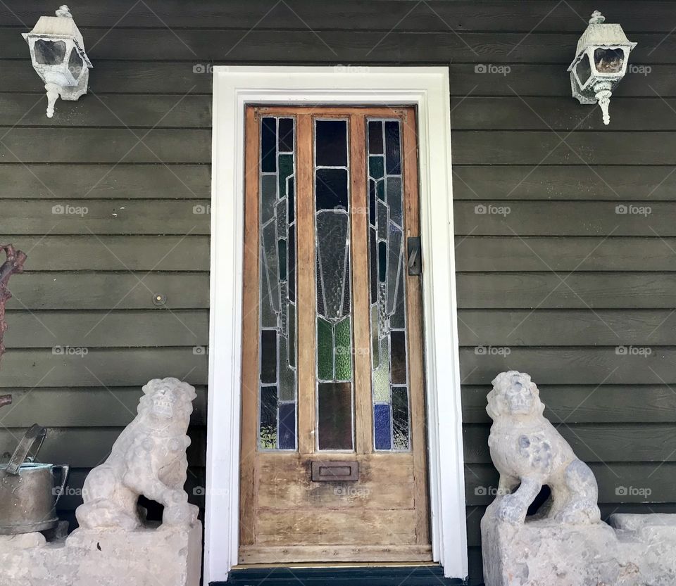 Wooden front door on a house with and statues on both sides