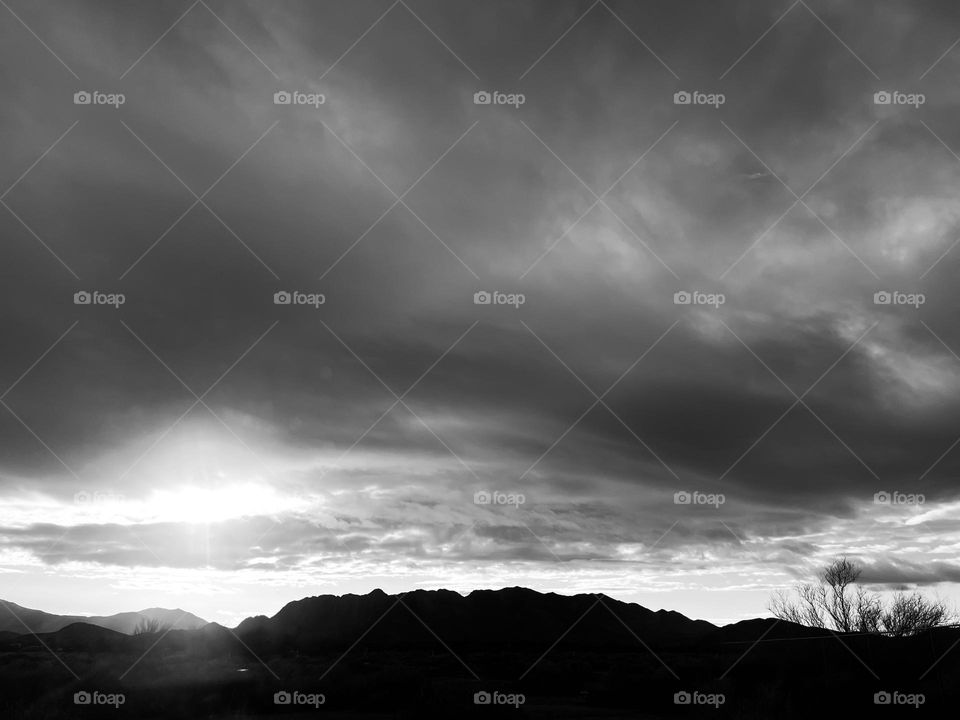 A black and white photo of mountains with clouds above. 