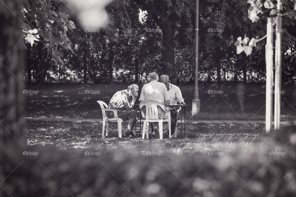 Elder men playing chess in the shades