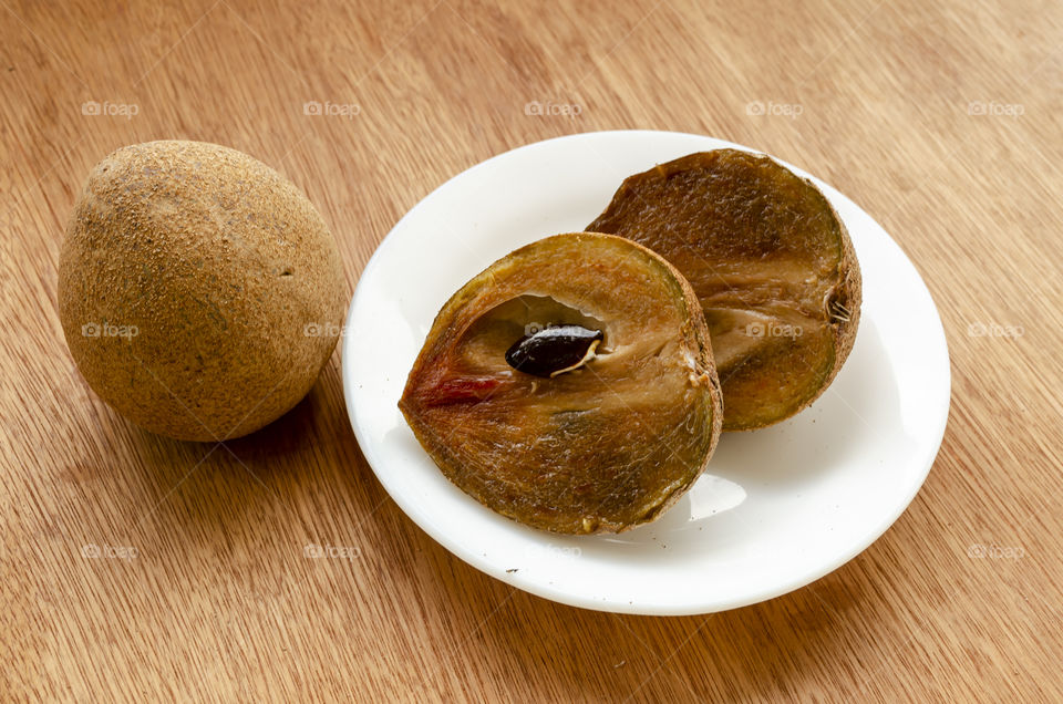 Naseberry Whole Fruit On Desk And Cut Fruit In Saucer