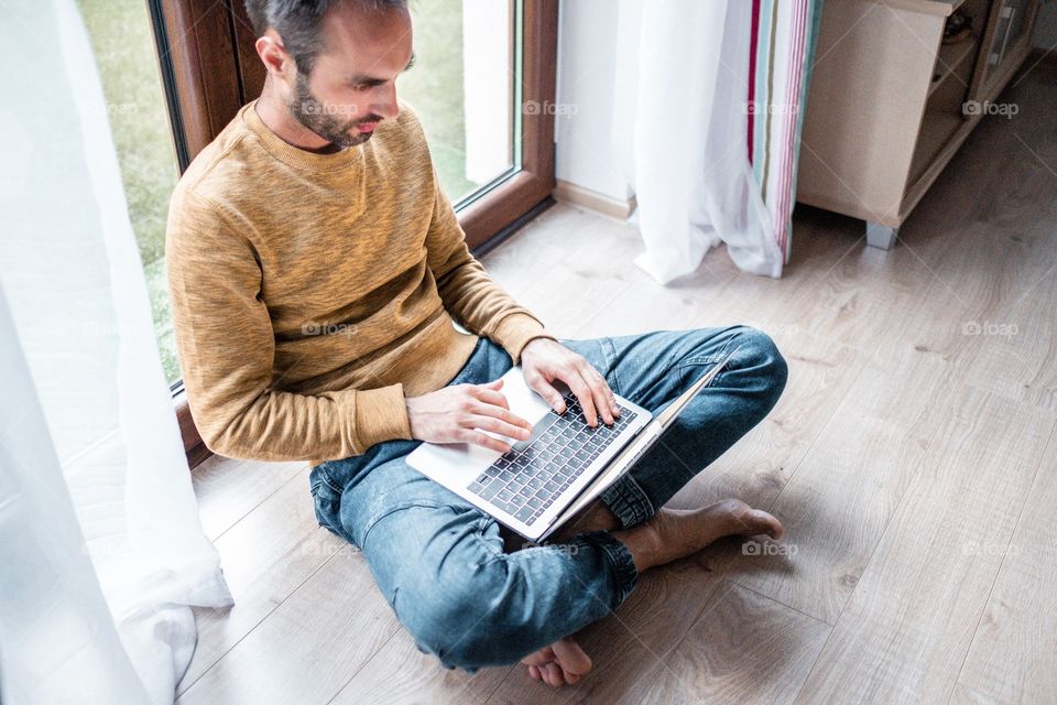 Bearded man sitting on the floor and working with the laptop