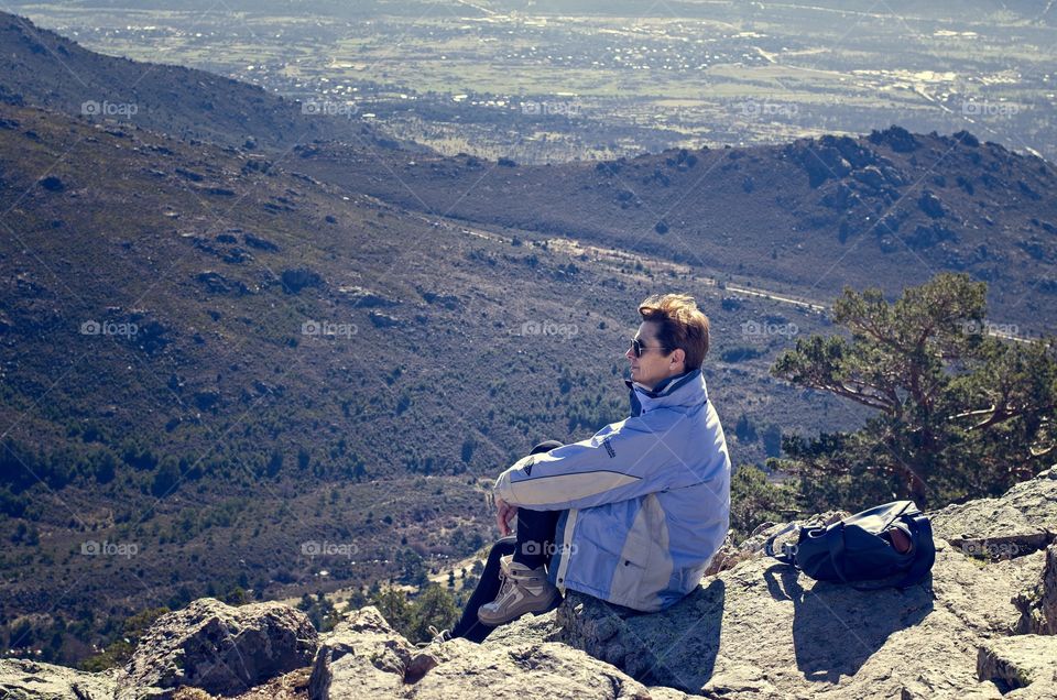 A woman seated on a rock enjoys the view of the mountains 