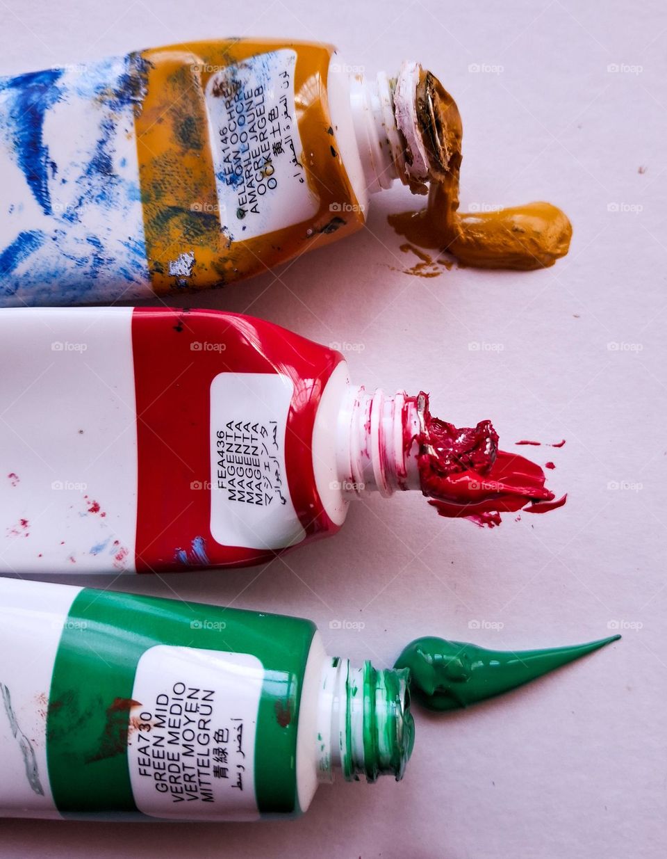 The contrast of complementary colors, namely green and red, is shown through open tubes of acrylic paint.