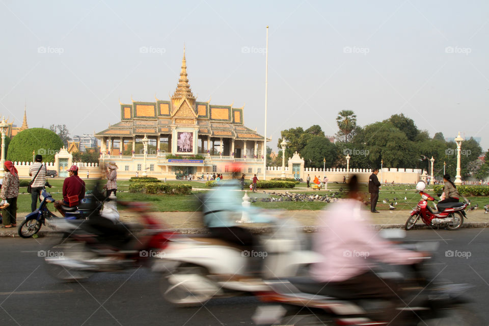 Commuters speed past the Royal Palace complex in Phnom Penh, capital of Cambodia