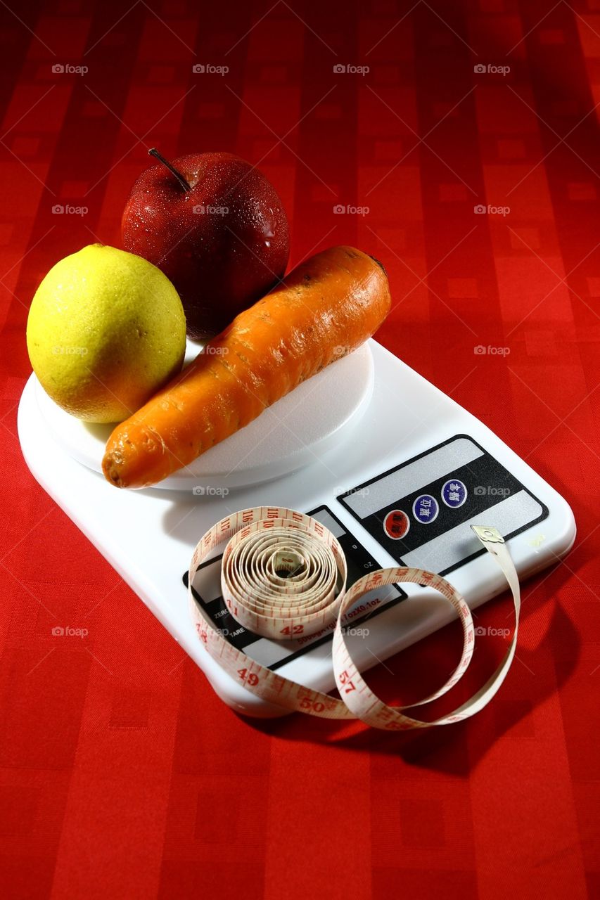 Fruits and vegetables in a weighing scale and a measuring tape