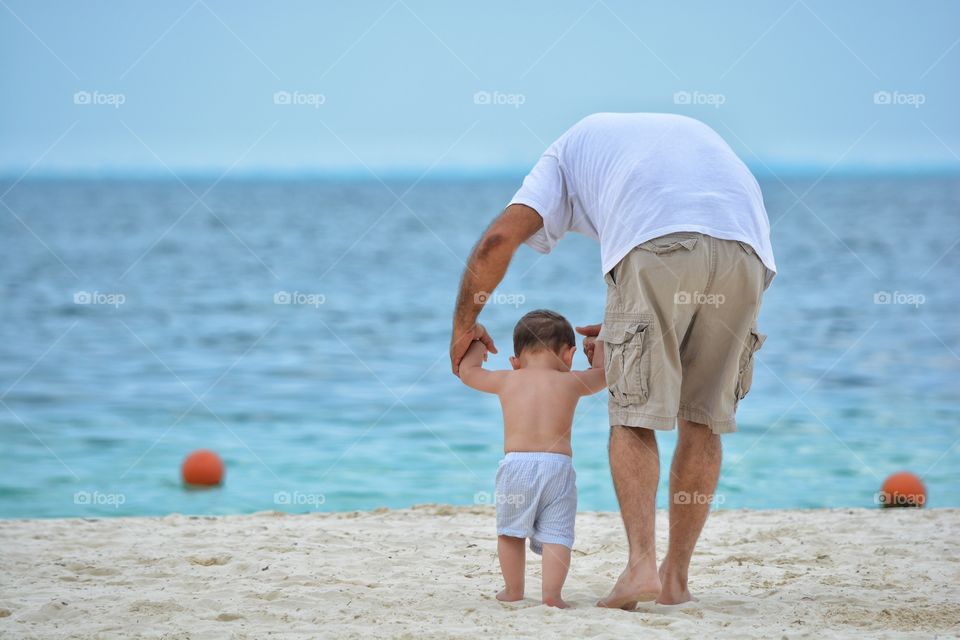 Child walking with his father at beach