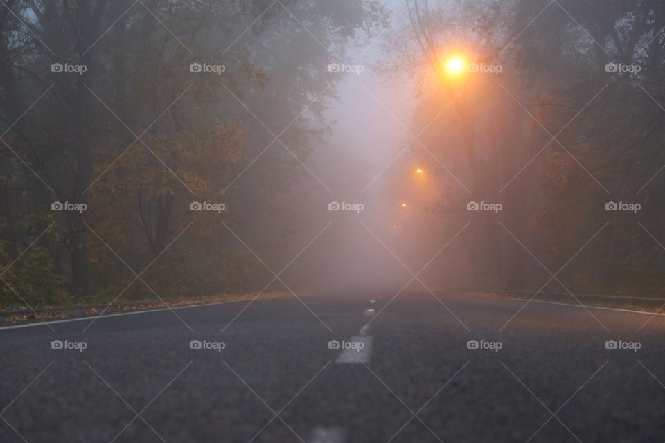 empty asphalt road with yellow lamps and fog