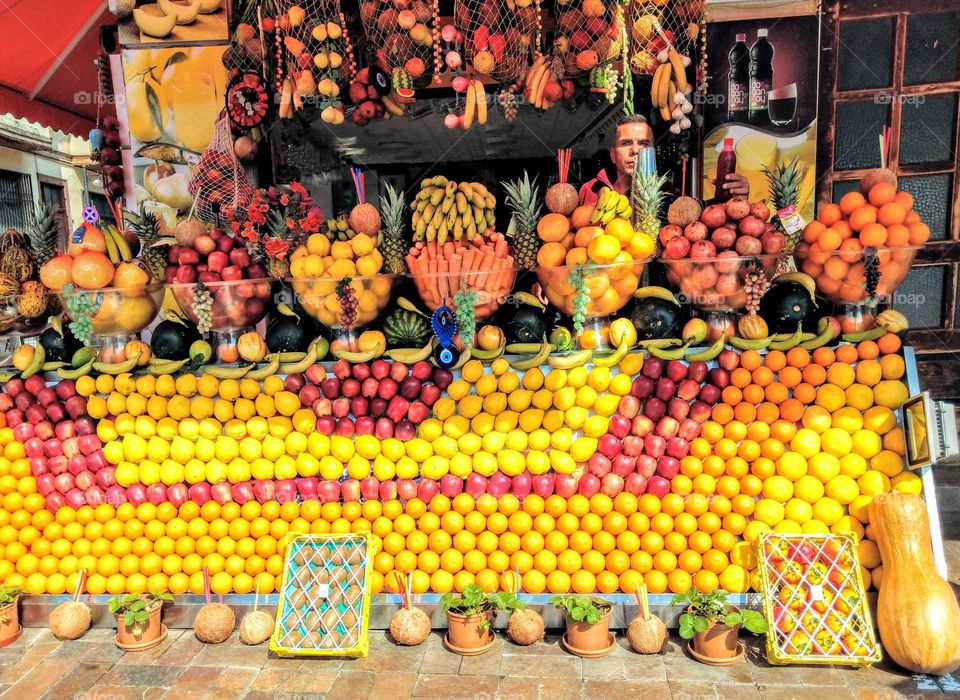 fruits:  encountering an interesting fruit stand on travel. the boss designed and arranged all fruits using all full stand space, had a wonderful pattern.I think the boss should very love his fruits, his work. it wasn't easy to arrange many fruits.