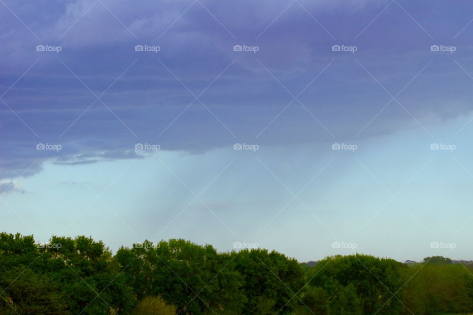 Distant Downpour - an area of heavy rain is seen coming down from ominous clouds in the distance,  rural setting 