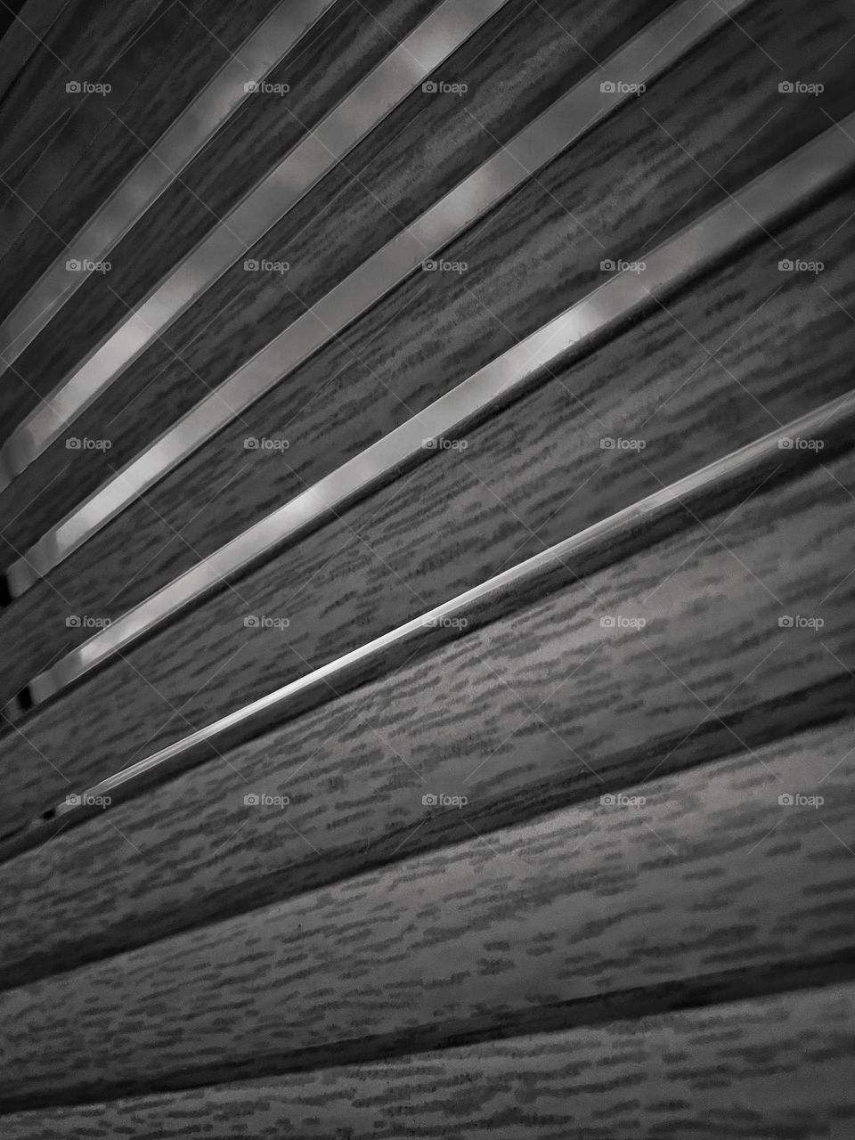 Horizontal wood effect blinds close up in black and white creating an air of mystery or drama