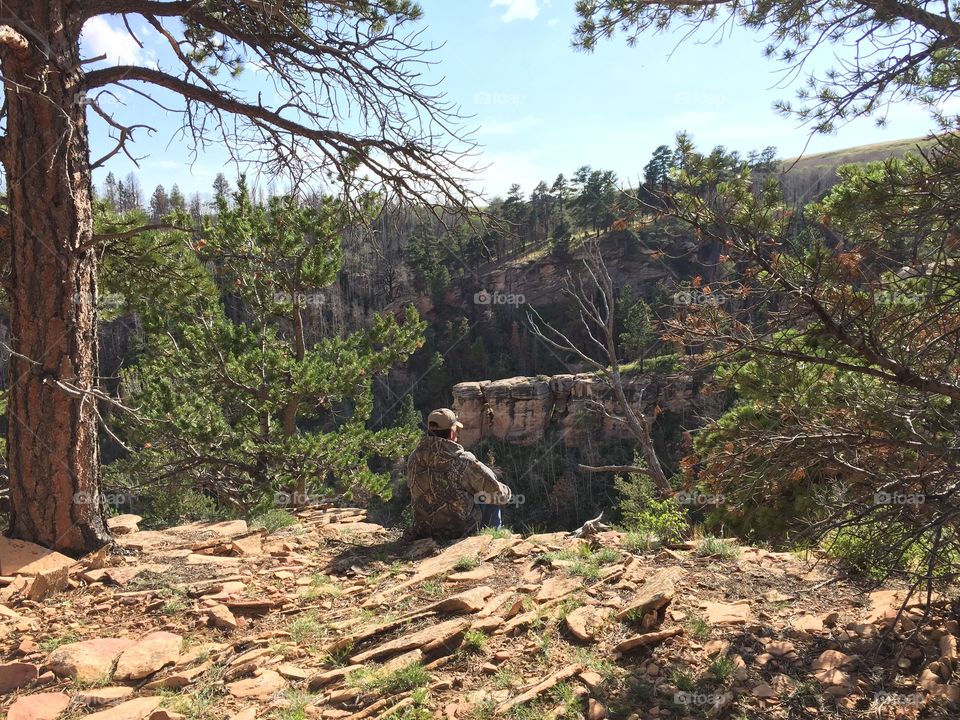 Hunter Sitting on Edge. A hunter sits patiently on the edge of a canyon 