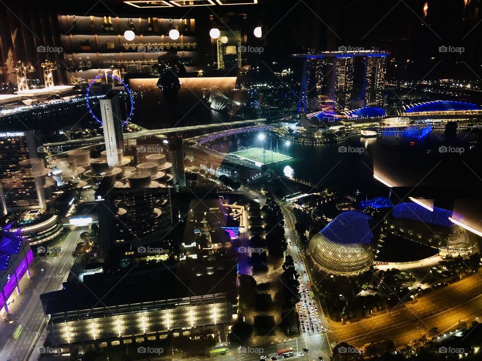 Singapore aerial views by night through the reflection of a glass window inside Raffles City shopping center 