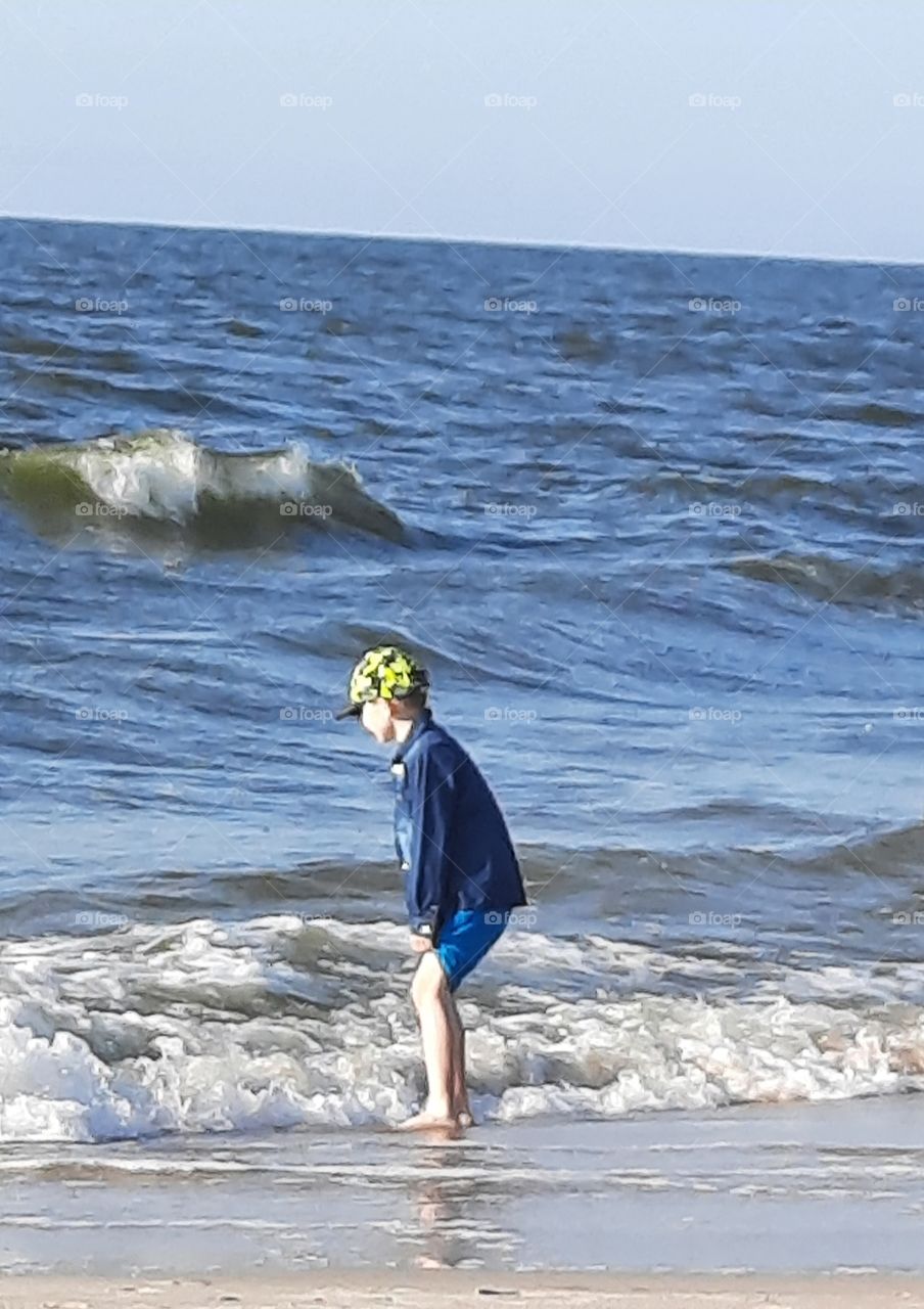 splash !  young boy playing with sea waves  on a sunny day