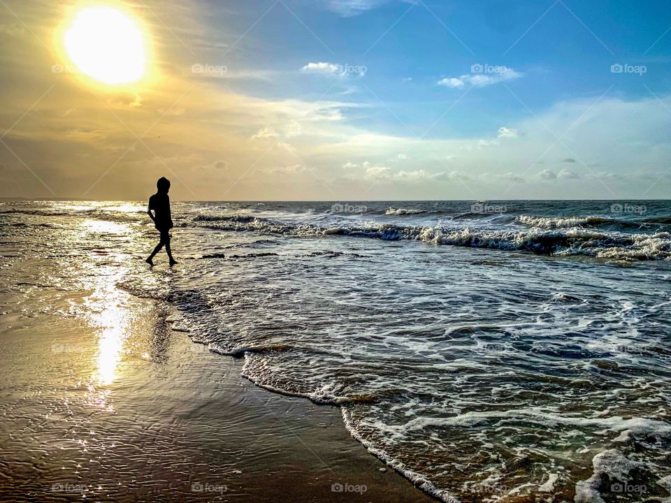 Silhouette of Brazilian boy playing with the sea waves in São Luís