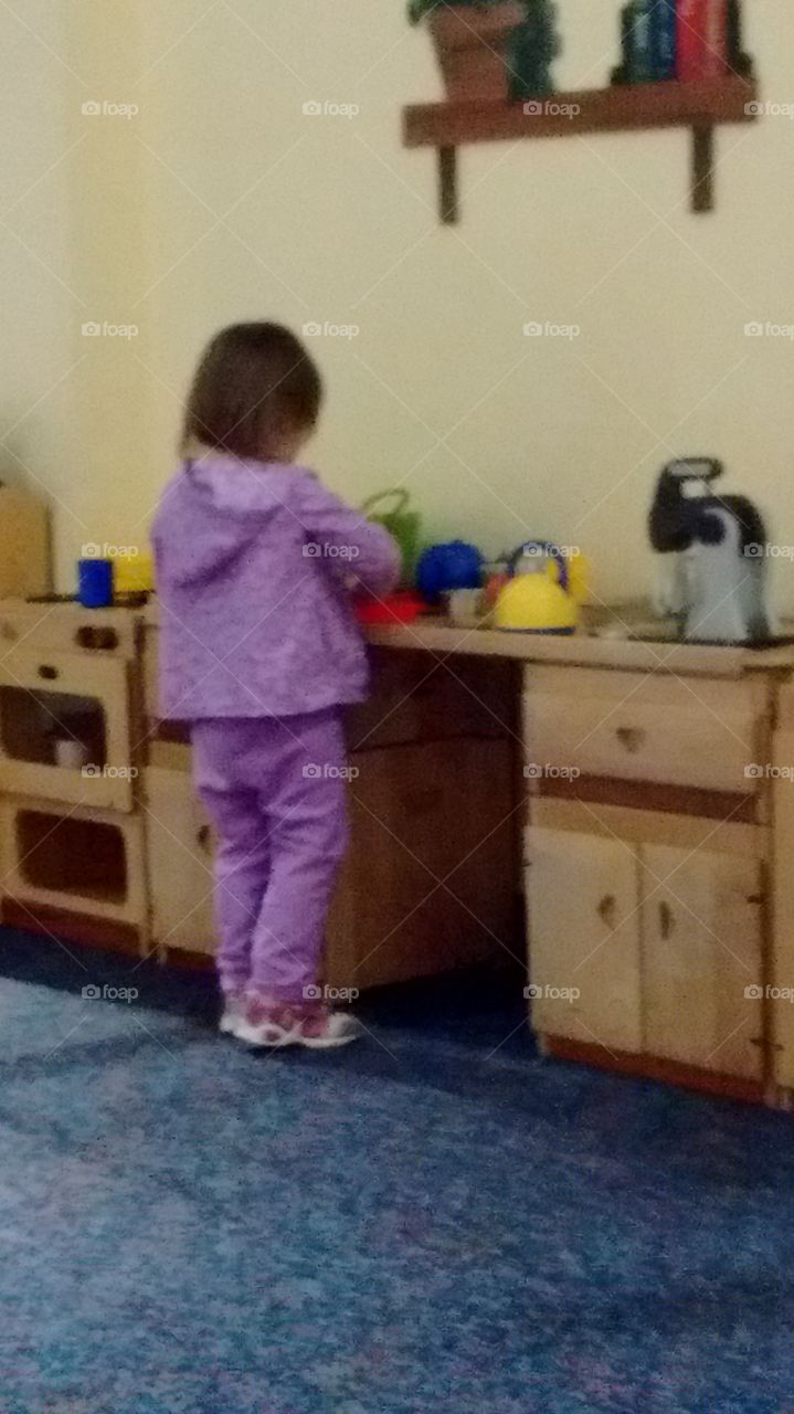 toddler playing in play kitchen