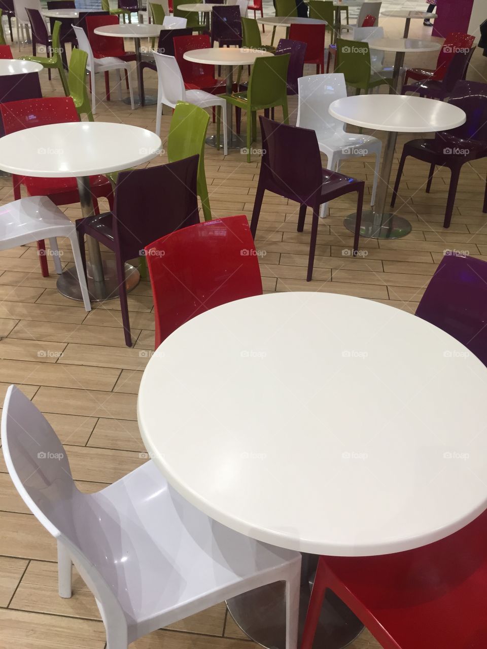 White tables and colorful chairs in a mall food zone