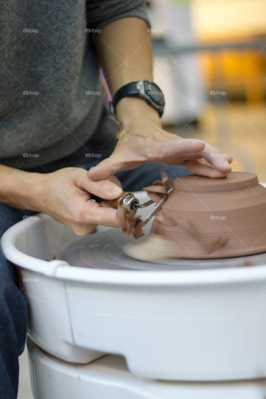 An artist works on a piece of pottery with tools