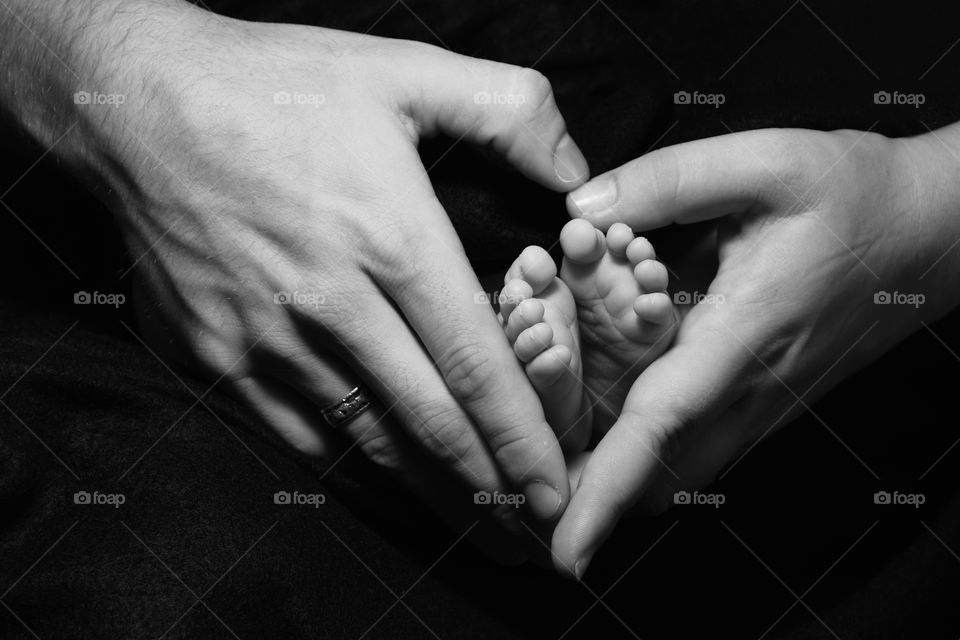Father holding infant baby’s feet black and white