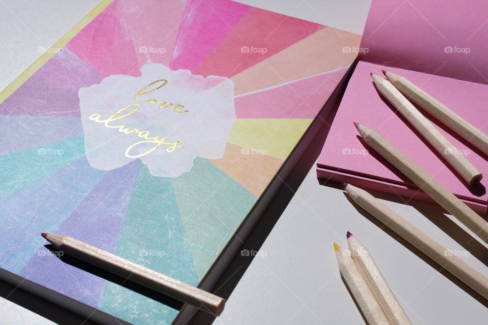 Notebook, pencils and notes in gentle colors: pink, blue and yellow