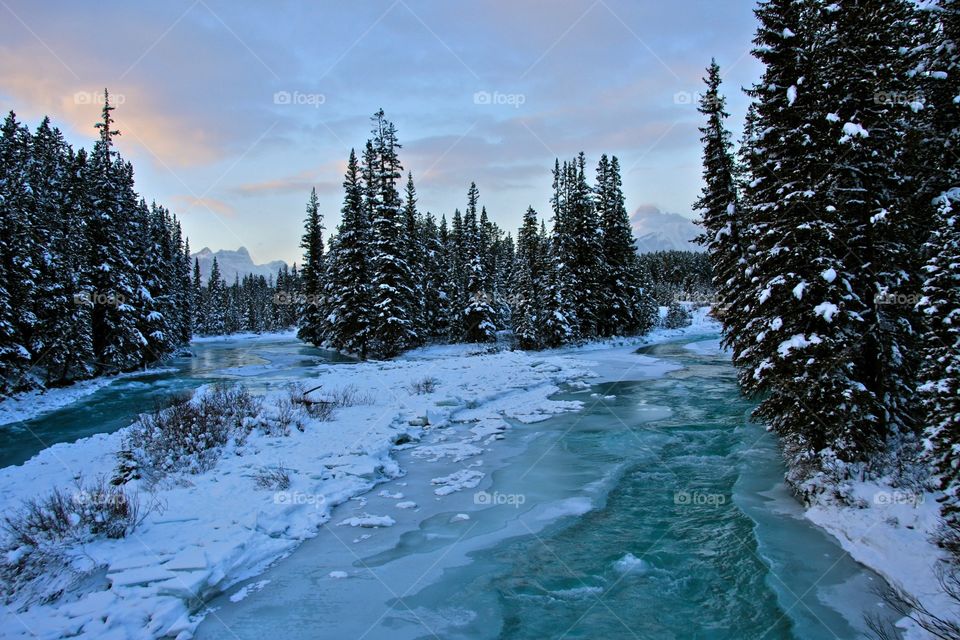 River flowing through the ice early evening on a cold winter’s day in Banff National Park