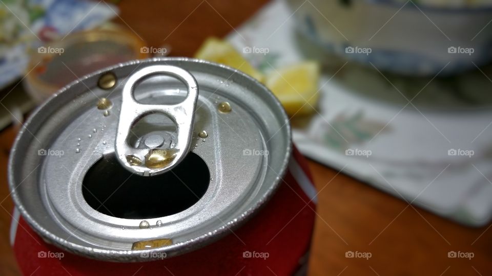 Opened soft drink can, over dinner.The can tab is visible.