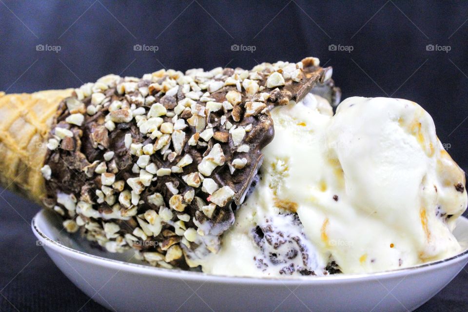 a bowl of ice cream with a chocolate covered waffle cone
