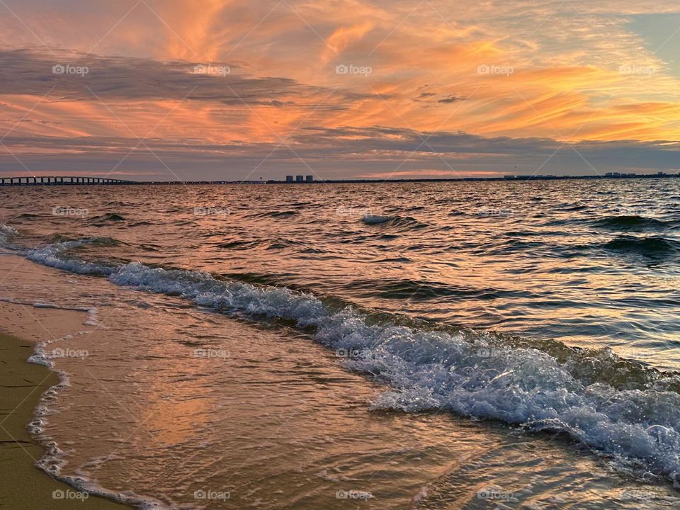 This evening the sun went down in a "peach-colored" fashion as the orange, wispy  clouds floated over the bay. The churning waves crashed the sandy beach