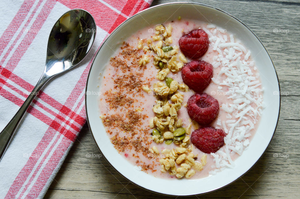 Fresh fruit smoothie bowl with flax seed, granola, raspberries, and coconut shavings