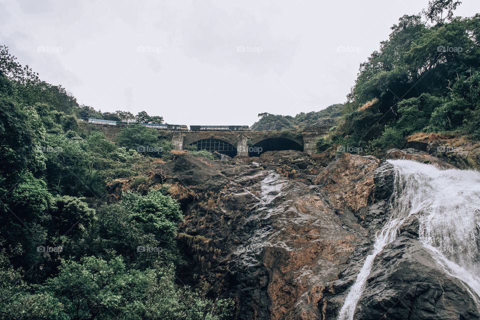 India riding a train on a mountain with a waterfall