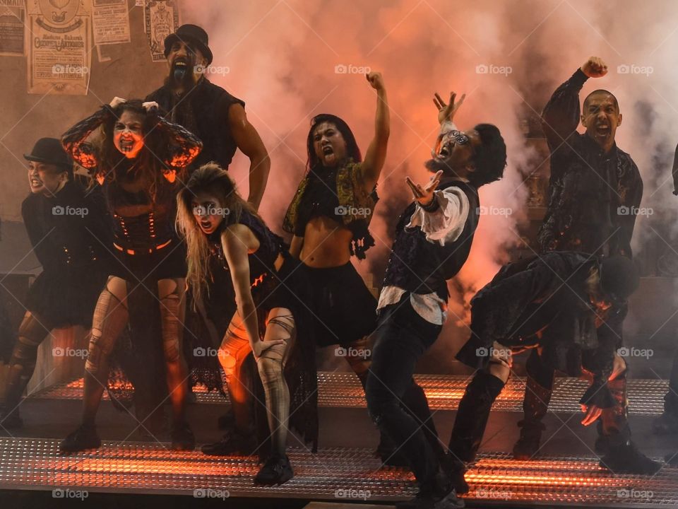 group of people in creepy Halloween costumes performing in a haze of red lights and fog