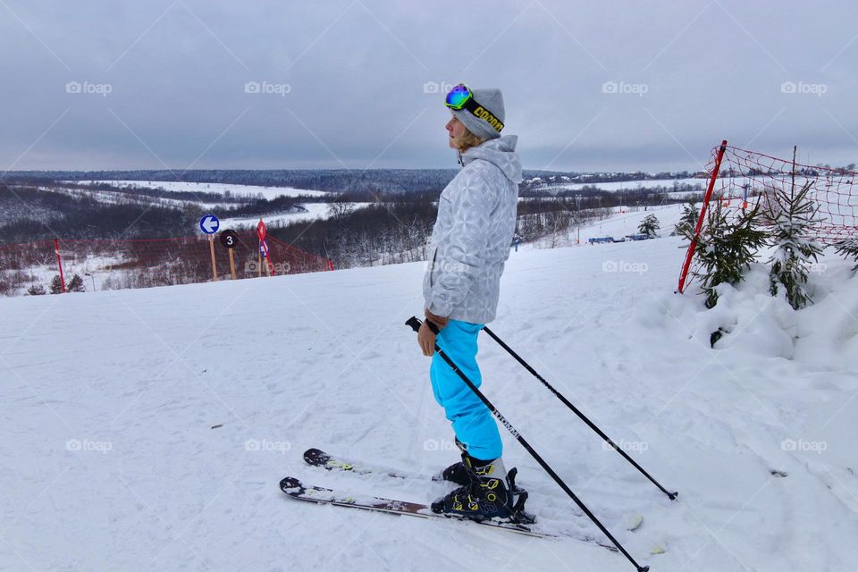 a young woman on skis stands on top of a ski slope