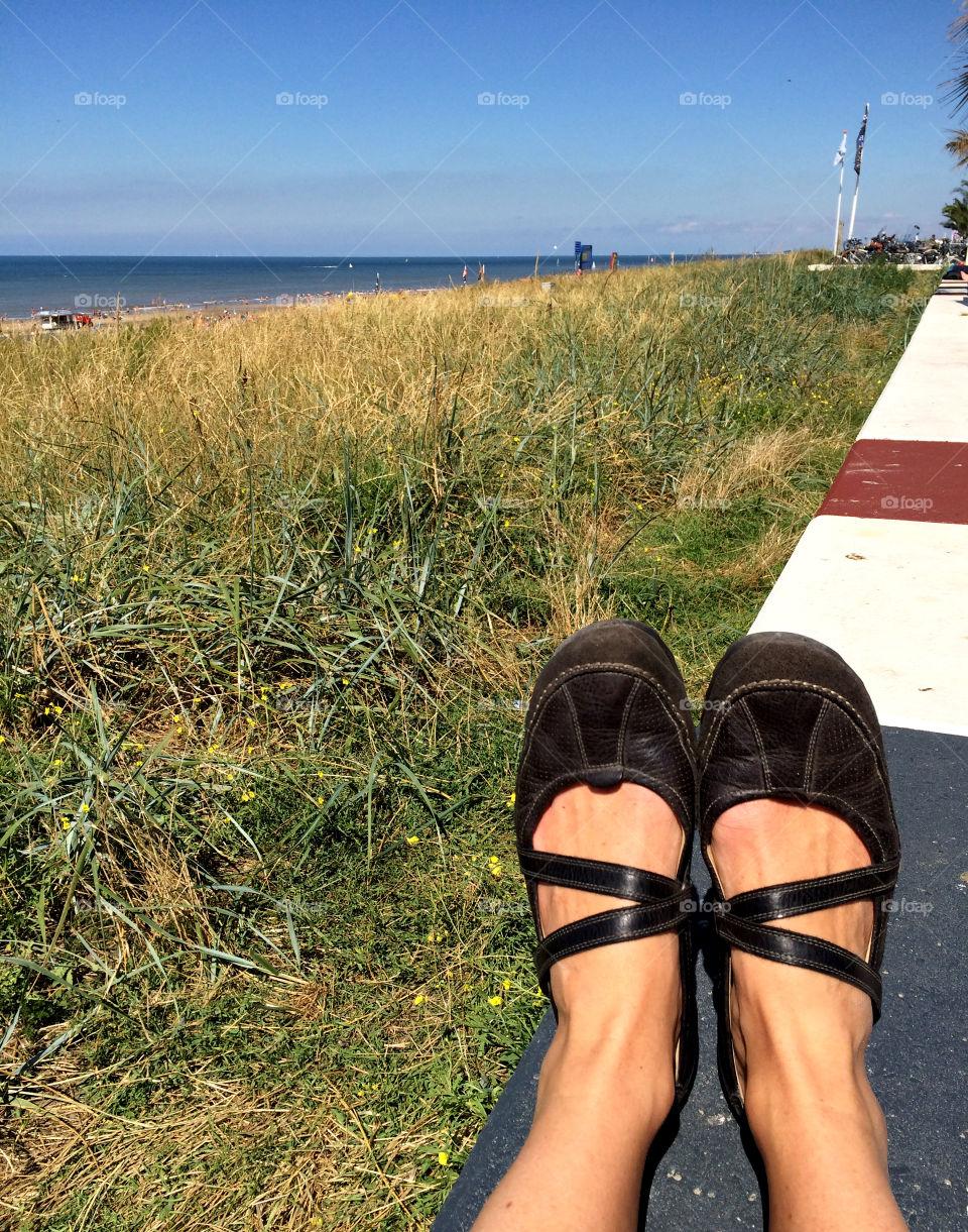 My feet on the striped wall on top of the dune watching the sea