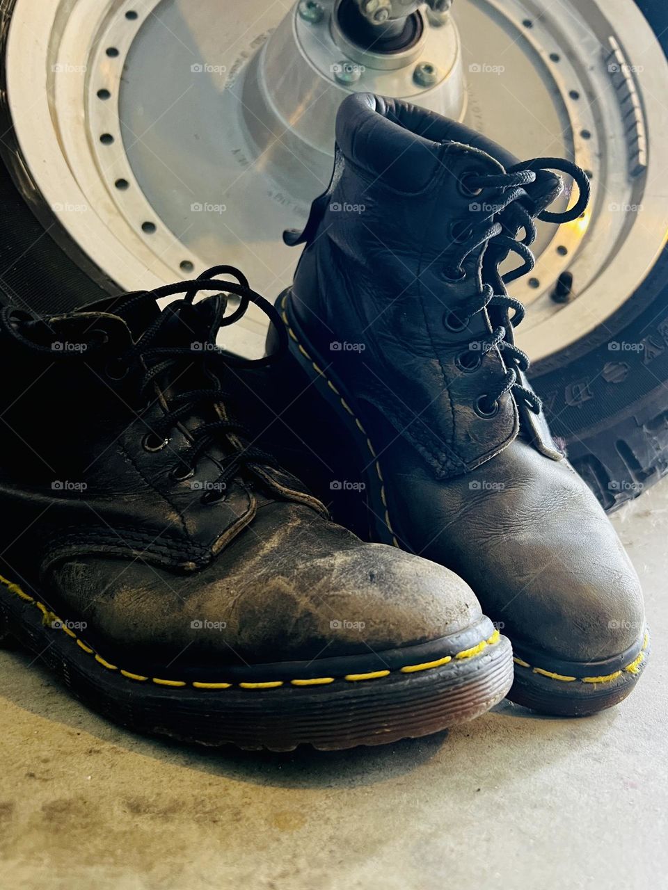 Closeup of worn, older Doc Marten classic boots with motorcycle in background 