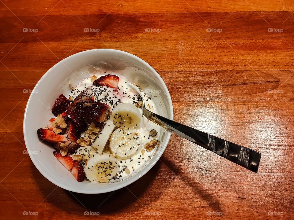 Delicious and healthy bowl of yougurt with banana slices and strawberries