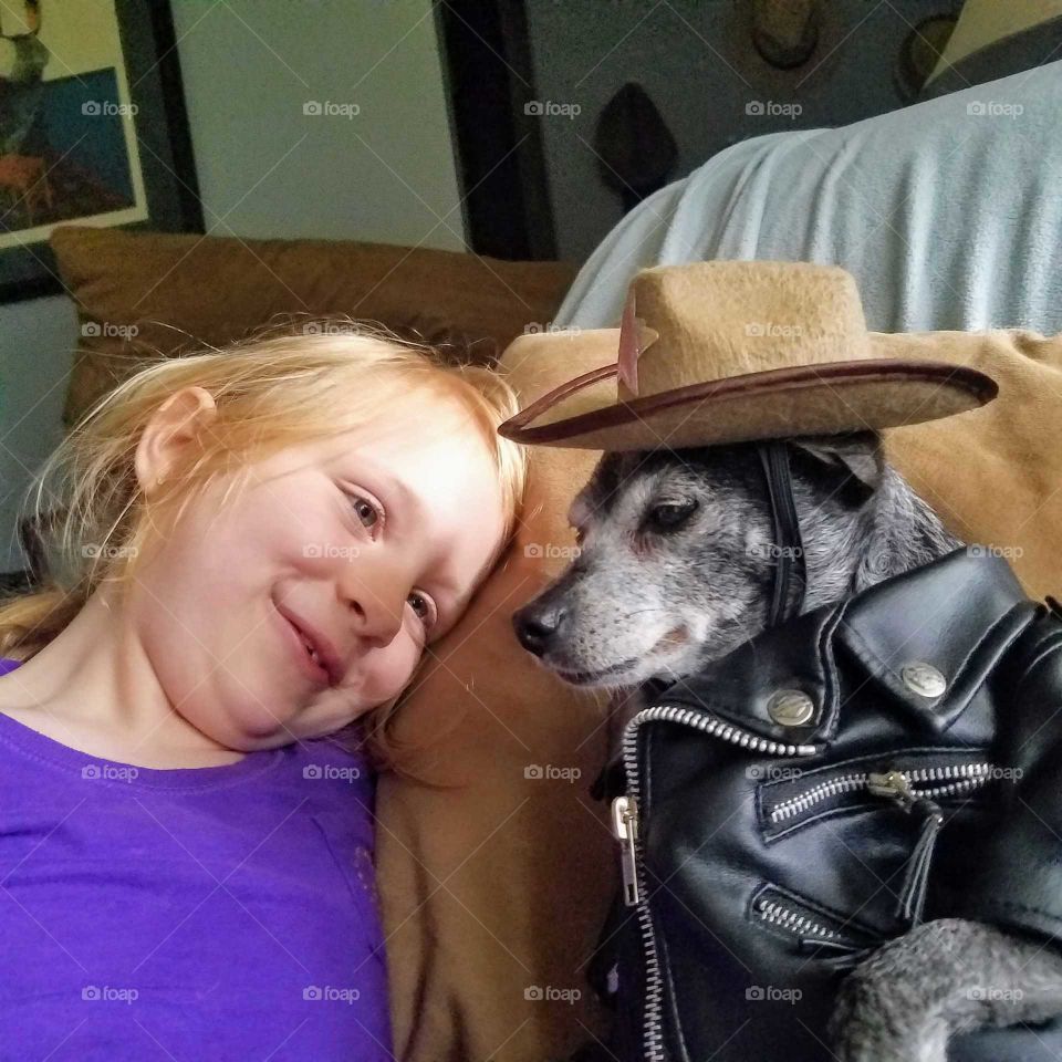 Girl admirers pet dog with leather jacket and a cowboy hat on