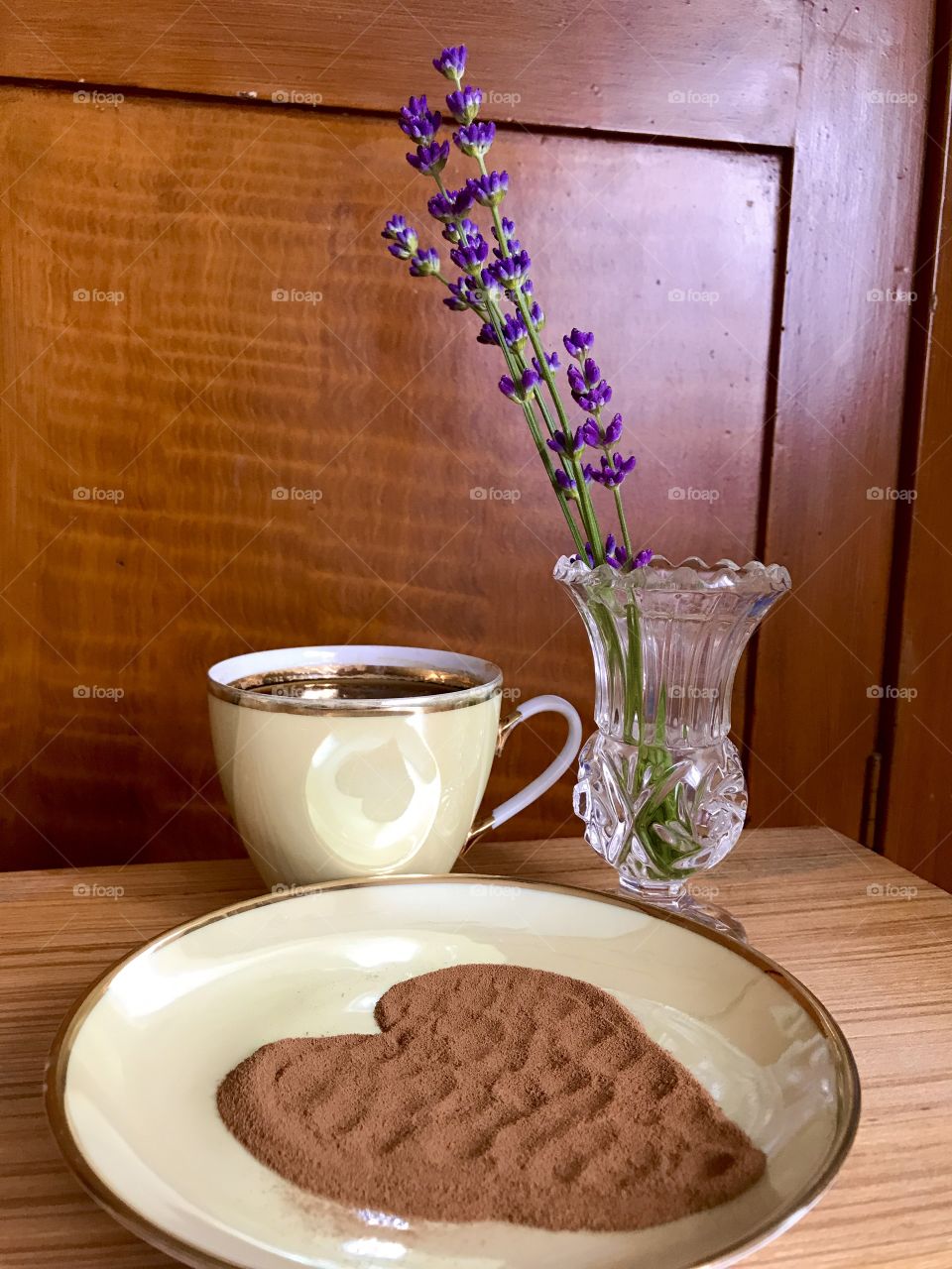 A golden cup of coffee is standing on a brown table. 