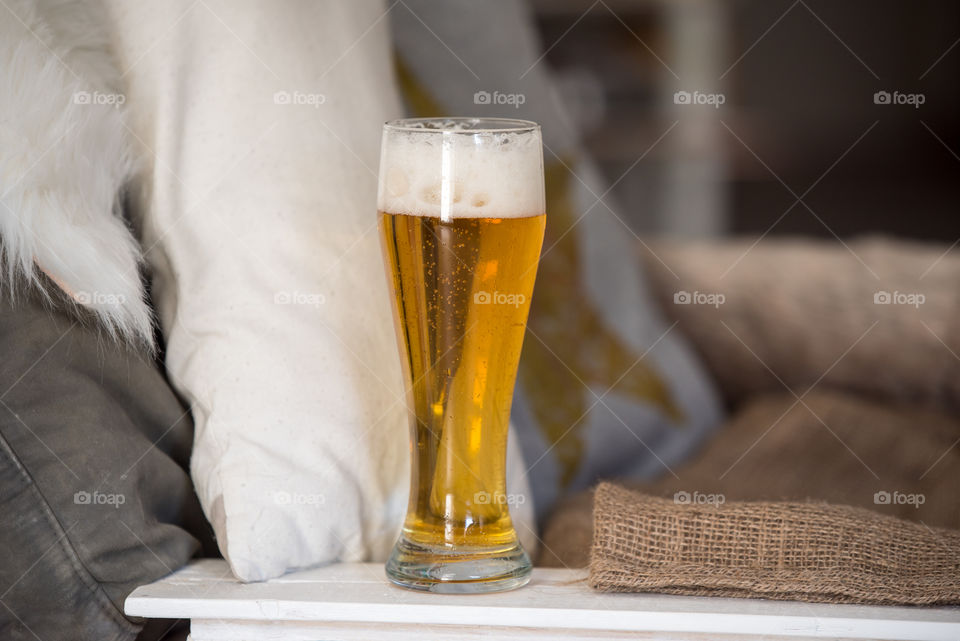 golden beer in a glass next to the white rustic chair