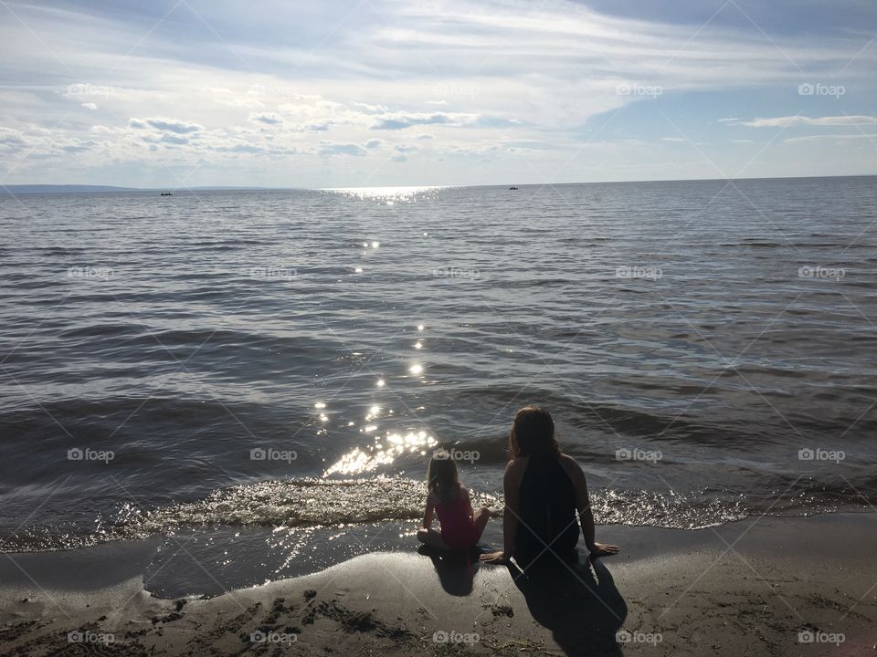 Mother and daughter sitting on the beautiful beaches of Slave Lake in northern Alberta, Canada 